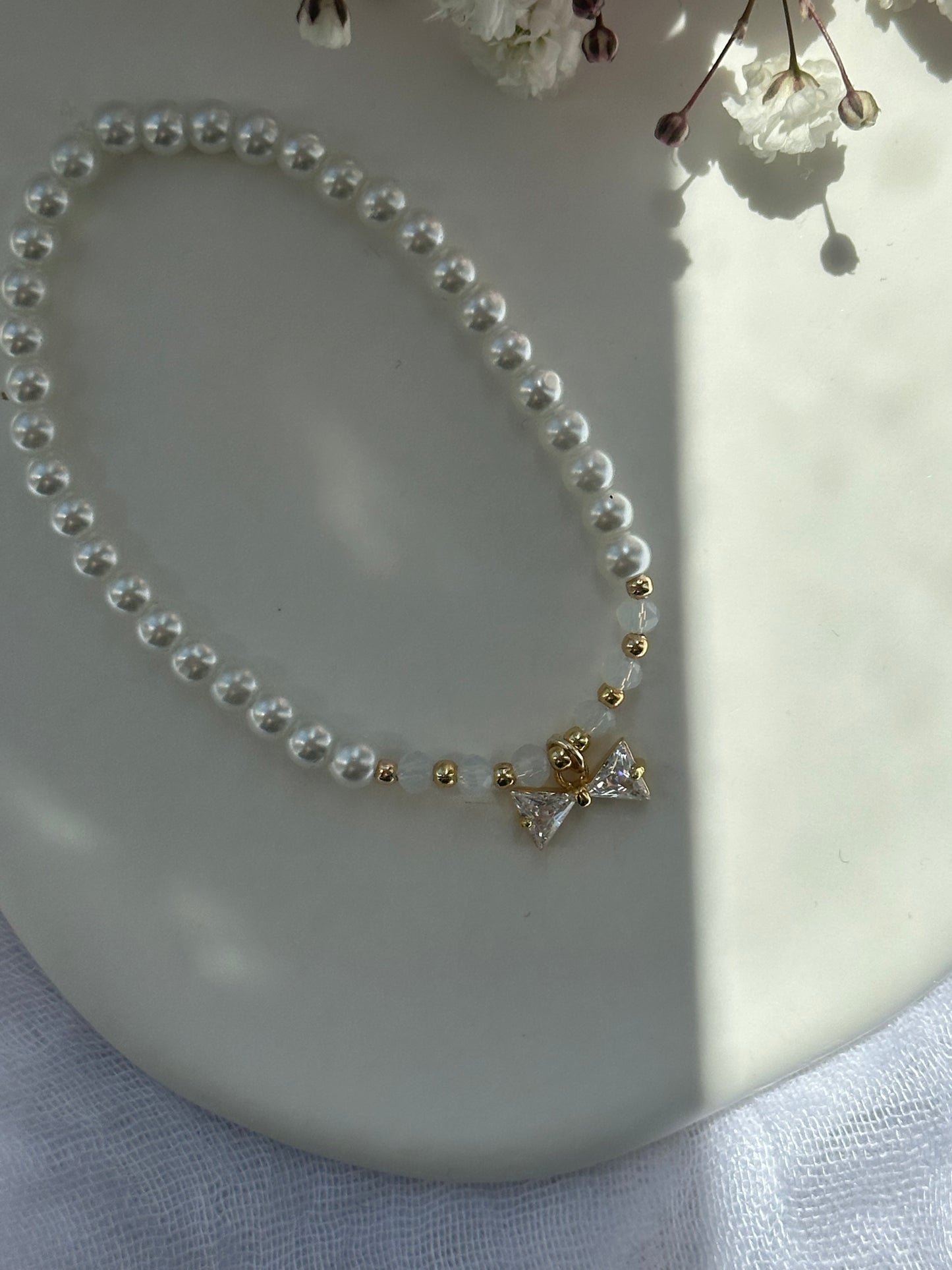 Perlenarmband mit Weißen Kristallperlen und Glasperlen und goldenen Details + Schleifen Anhänger - 10761