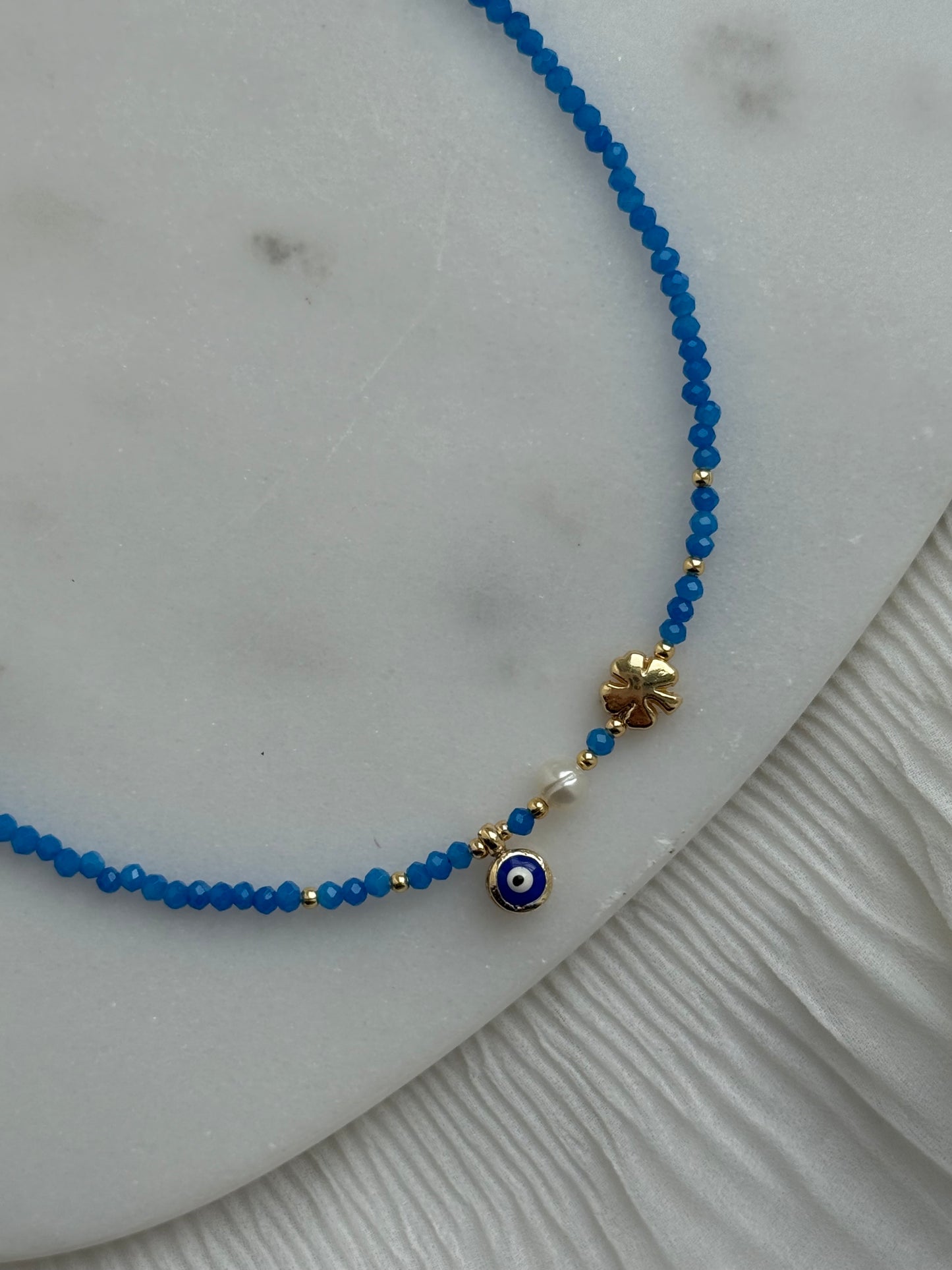 Perlenkette mit Blauen Kristallperlen, Goldenen Details + Nazar, Kleeblatt Anhänger - 111166