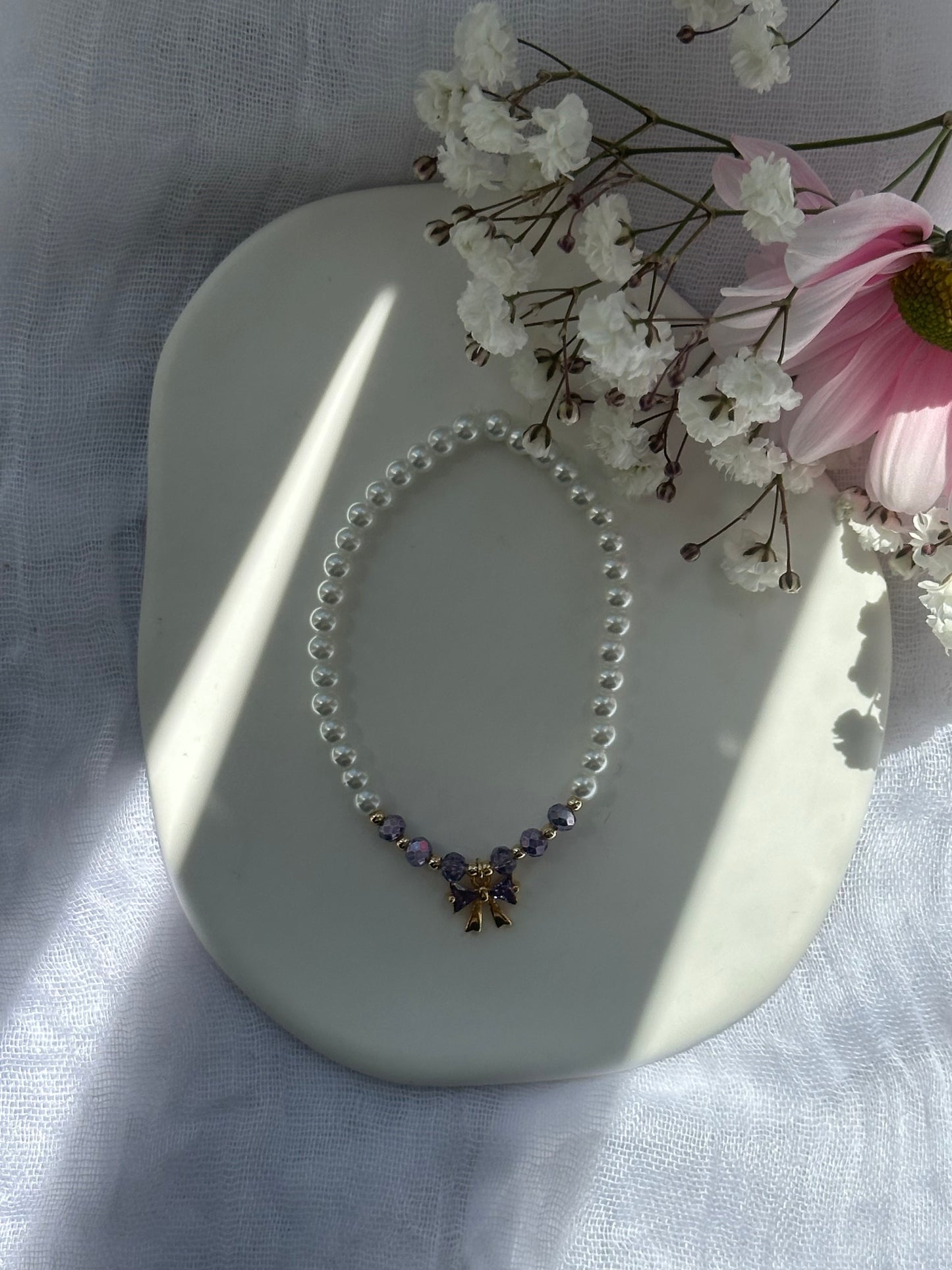 Perlenarmband mit Weißen Glasperlen und Lila Kristallperlen und goldenen Details + Schleifen Anhänger - 10733