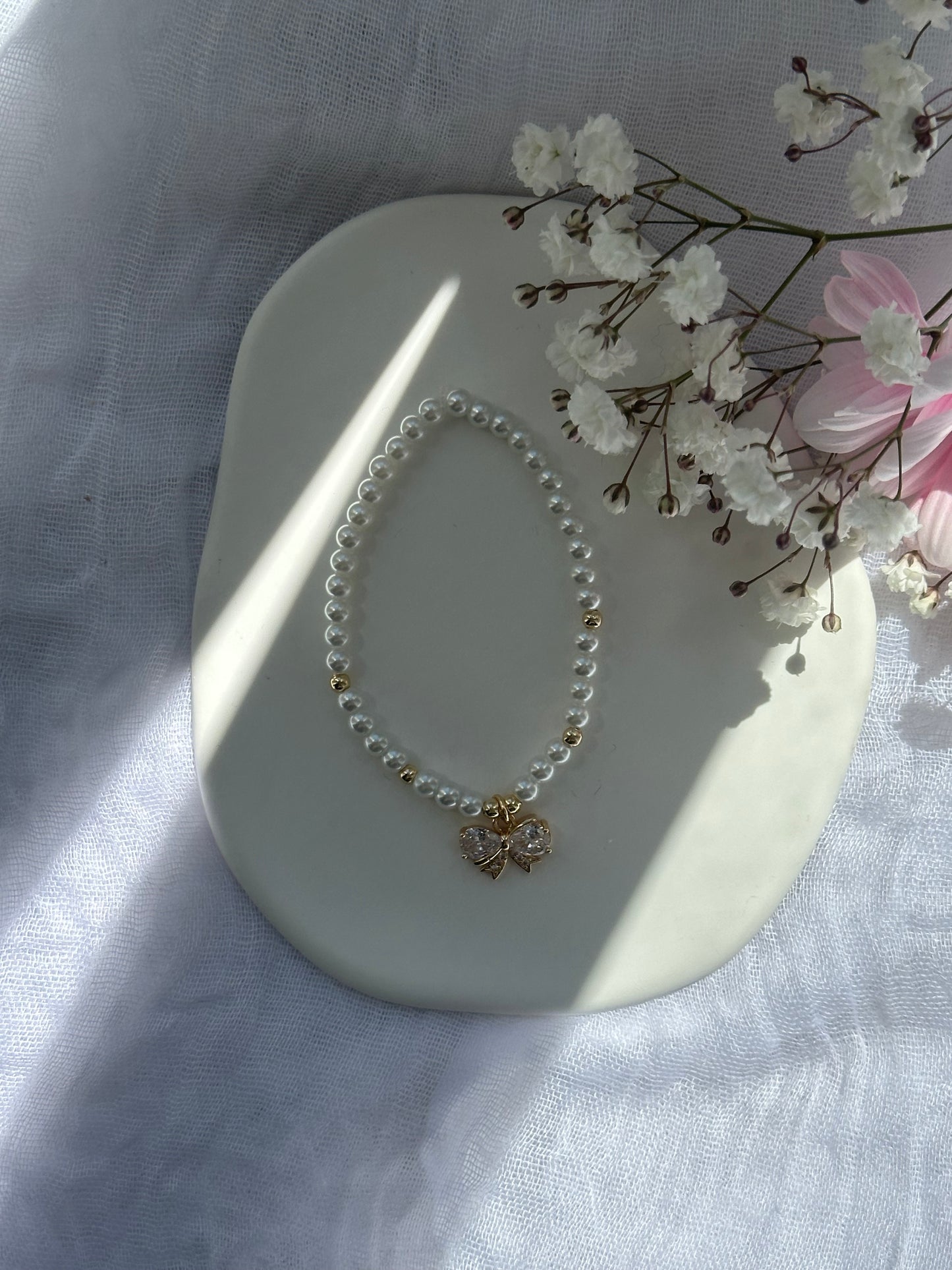 Perlenarmband mit Weißen Glasperlen und goldenen Details + Schleifen Anhänger - 10770